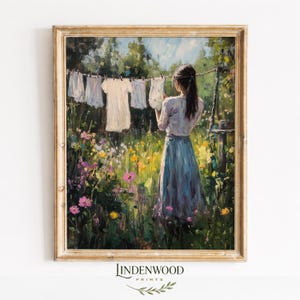 May include: A framed painting depicts a woman hanging laundry on a clothesline in a vibrant garden. The artwork features a palette of greens, blues, and yellows, with a focus on the woman and the clothes. The painting is signed "LINDENWOOD PRINTS".