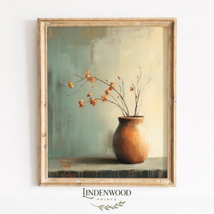 May include: An art print featuring a still life composition. A brown vase holds delicate branches with orange blossoms. The background has a muted color palette of teal, beige, and brown. The print is framed in a gold-toned wooden frame. The text "LINDENWOOD PRINTS" is at the bottom.