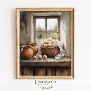 May include: A framed still life painting depicts a rustic kitchen scene. A woven basket overflows with onions, next to terracotta pots and onions on a wooden surface. A window with a view of the outdoors is in the background.