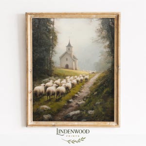 May include: A framed landscape painting depicts a flock of sheep walking along a path towards a small white church. The artwork, in a gold-colored frame, has a pastoral theme with trees and a soft, muted color palette.