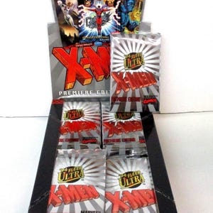 Puede incluir: Una caja expositora de cromos X-Men Premiere Edition Fleer Ultra de 1994. La caja es negra y roja, con el logo de X-Men en rojo. Los paquetes son plateados con el logo de X-Men y la marca Marvel Comics.