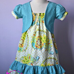 May include: A turquoise and white patterned dress with a matching turquoise bolero jacket. The dress has a ruffled hem and a floral print.