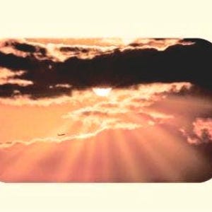 Puede incluir: Una dramática escena de atardecer con nubes oscuras y texturizadas y el sol asomando, proyectando rayos dorados. Se ve una pequeña silueta de un avión, lo que añade una sensación de escala al vasto cielo. La paleta de colores es cálida, con tonos de naranja, rojo y marrón.