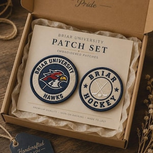 May include: A Briar University Patch Set in a cardboard box. The set includes two circular embroidered patches: one featuring a hawk mascot with the text Briar University Hawks, and one with crossed hockey sticks and the text Briar Hockey.