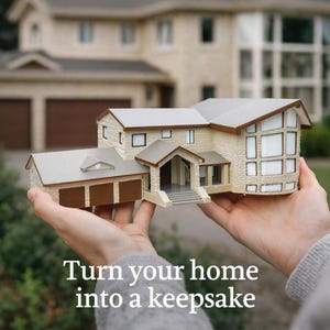 May include: A detailed miniature house model with a beige stone facade, a grey roof, and brown garage doors. The model is held in front of a blurred background of a real house. The text "Turn your home into a keepsake" is at the bottom.
