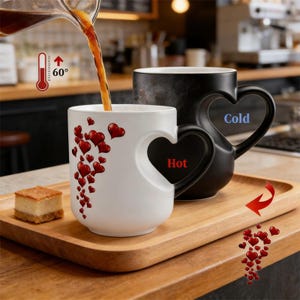 May include: Two heart-handled mugs, one white with red hearts and the word "Hot", the other black with the word "Cold". Coffee is being poured into the white mug. A thermometer reads 60 degrees.