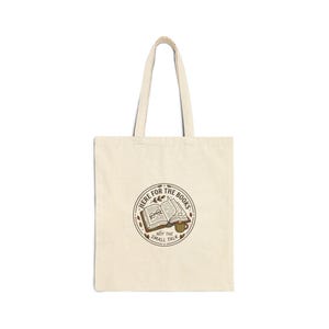 May include: Cream-colored tote bag with a circular graphic featuring an open book, glasses, and a coffee cup. The text reads "Here for the books, not the small talk."