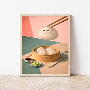 May include: A whimsical art print featuring a fluffy white cat designed as a dumpling, held by chopsticks. Below, a wooden steamer basket holds several dumplings, accompanied by small bowls of dipping sauce and sliced cucumbers. The background has pink and teal geometric shapes.