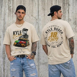 May include: Beige t-shirt featuring a graphic of Kyle Busch and his race car, with the text "In Memory Of Kyle Busch" and "Thank You For The Memories". The back of the shirt has a similar design with the number 18.