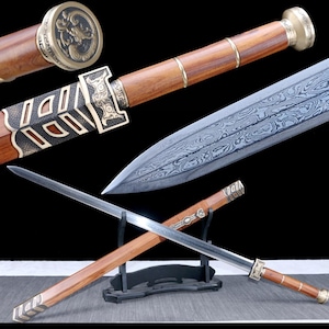 May include: A detailed image of a decorative sword with a wooden handle and a patterned blade. The handle features brass accents and a circular end cap with a dragon design. The blade has a unique, textured pattern. The sword is displayed on a black stand.