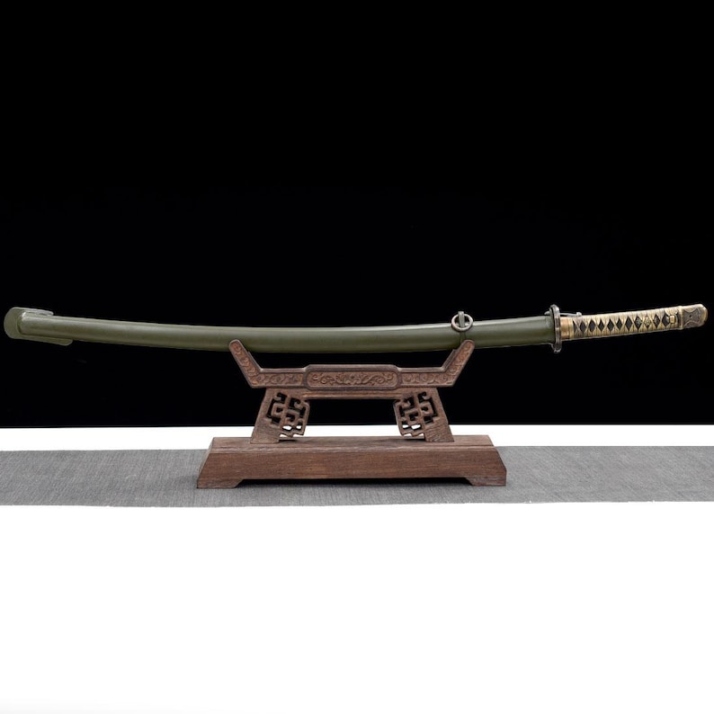 May include: A Japanese katana sword with a green scabbard and a decorative handle, resting on a wooden stand. The blade is slightly curved, and the handle features a diamond pattern. The stand has an ornate design.