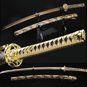 May include: Three Japanese katanas with gold-colored hilts and blades. The handles are wrapped in a snakeskin pattern. The blades are displayed on black stands, showcasing the intricate details of the swords.