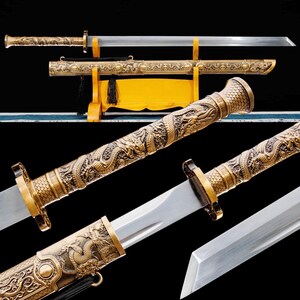 May include: An ornate sword with a gold-colored handle and scabbard, featuring intricate dragon carvings. The blade is silver and straight. The sword rests on a yellow wooden stand, with a black tassel hanging from the scabbard.