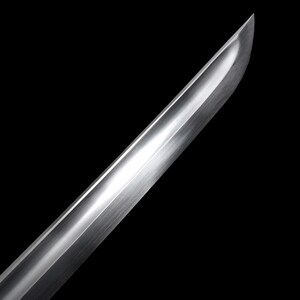 May include: Close-up of a polished, silver-colored sword blade against a black background. The blade has a curved edge and a reflective surface, catching the light. The image highlights the craftsmanship and sharpness of the weapon.