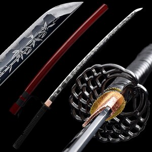 May include: A detailed view of a Japanese katana sword. The blade has intricate etched designs and a silver finish. The handle is wrapped in black cord, and the scabbard is a deep red. The guard is a decorative, openwork design.
