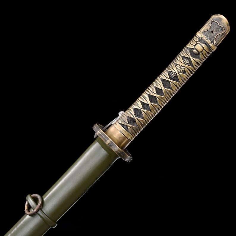 May include: Close-up of a Japanese katana sword. The handle is wrapped in a diamond pattern with a gold finish. The scabbard is olive green. The sword's hilt and fittings have an antique gold finish. The blade is not visible.