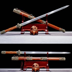 May include: Two ornate swords with wooden handles and scabbards are displayed on a wooden stand. The blades are silver, and the handles and scabbards are a rich brown with decorative metal accents. A small, decorative statue sits in front.