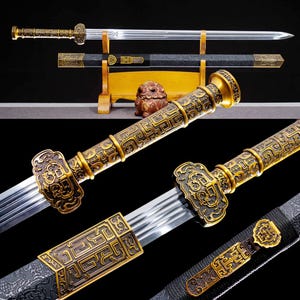 May include: An ornate sword with a gold-colored handle and accents, and a silver blade. The sword is displayed with its black scabbard on a wooden stand. The handle and scabbard feature intricate patterns.