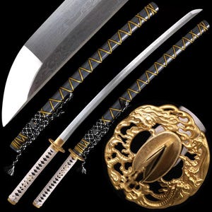 Op de afbeelding: Gedetailleerde afbeelding van een katana-zwaard. Het zilveren lemmet heeft een zichtbaar patroon. De handgreep is omwikkeld met wit en zwart koord. De schede is zwart met gouden accenten. De tsuba, ofwel de handbeschermer, is goudkleurig en heeft een drakenontwerp.
