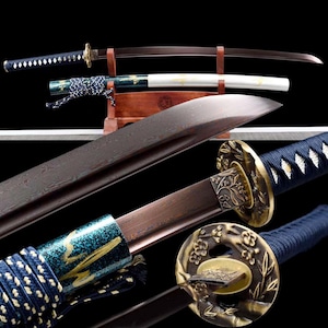 May include: An assortment of Japanese katana swords. The blades have a dark, metallic finish, with ornate gold-colored guards and handles wrapped in blue and white cord. One sword is displayed in a wooden stand.