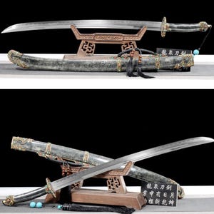 May include: Two ornate swords with curved blades, displayed on a wooden stand. The swords have decorative handles and sheaths, with intricate detailing and embellishments. The blades are silver, and the handles are black.