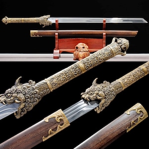 May include: An ornate sword with a polished steel blade and a decorative handle featuring a dragon motif. The handle and scabbard are detailed with gold-colored metal accents and intricate patterns. The sword is displayed on a wooden stand.