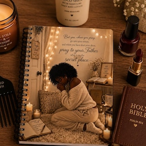 May include: A spiral-bound journal with an illustration of a person praying, surrounded by candles and a Bible. Other items include a black comb, a jar candle, a bottle of lotion, nail polish, and lipstick. The journal has the text "But you, when you pray, go into your room, and when you have shut your door, pray to your Father who is in the secret place."