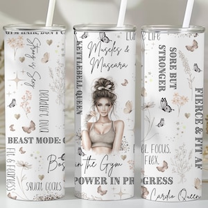 Pode incluir: Um copo branco com canudo, com uma mulher em roupa de ginástica e frases motivacionais como "Muscles & Mascara" e "Beast Mode". O design inclui borboletas, flores e texto em escrita cursiva.