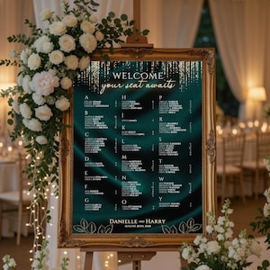 May include: A framed seating chart with a teal and gold design. The chart reads "WELCOME your seat awaits" and lists names alphabetically. The frame is gold, and the background has a flowing, textured pattern. The wedding date is displayed at the bottom.