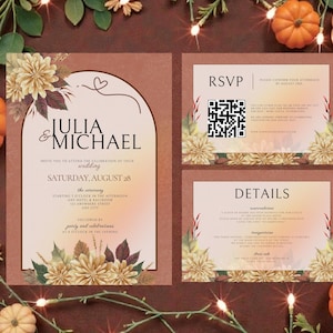 May include: Wedding invitation suite featuring a main invitation card with the names "Julia & Michael" and event details, along with RSVP and details cards. The design includes floral accents, a warm color palette, and decorative pumpkins.
