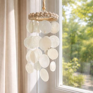 Peut inclure: Un carillon éolien décoratif avec une esthétique côtière naturelle. Il comprend un anneau tissé, une série de disques ronds en coquillage blanc cassé et une corde naturelle pour la suspension. Le design est simple et élégant, pour l'intérieur ou l'extérieur.