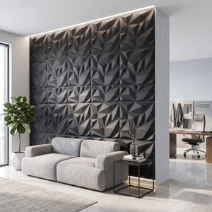 May include: A charcoal gray wall featuring a three-dimensional geometric pattern of triangular facets. The wall serves as a backdrop for a light gray sofa, a black metal side table with a glass vase, and a potted plant in a white geometric planter.