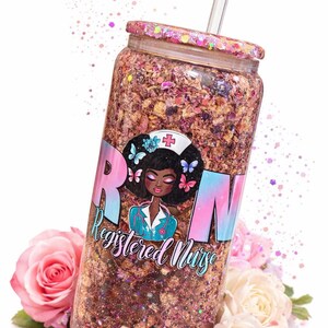 May include: A glitter-filled tumbler with a Registered Nurse design. The tumbler features a clear straw and a lid with glitter accents. The design includes the letters "RN" and an illustration of a nurse with butterflies. Pink roses and petals surround the tumbler.