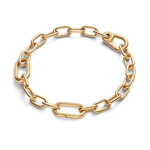 May include: A gold-toned chain link bracelet featuring elongated oval links with a polished finish. The bracelet includes a functional lobster clasp closure engraved with the word Pandora, allowing for the attachment of charms or pendants.