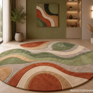 Puede incluir: Una alfombra circular grande con un patrón abstracto en capas de formas onduladas y curvas en tonos naranja terracota, verde salvia, beige y crema. La alfombra tiene una superficie texturizada y copetuda e incluye el texto RUGSSTUDIOHANDMADE.
