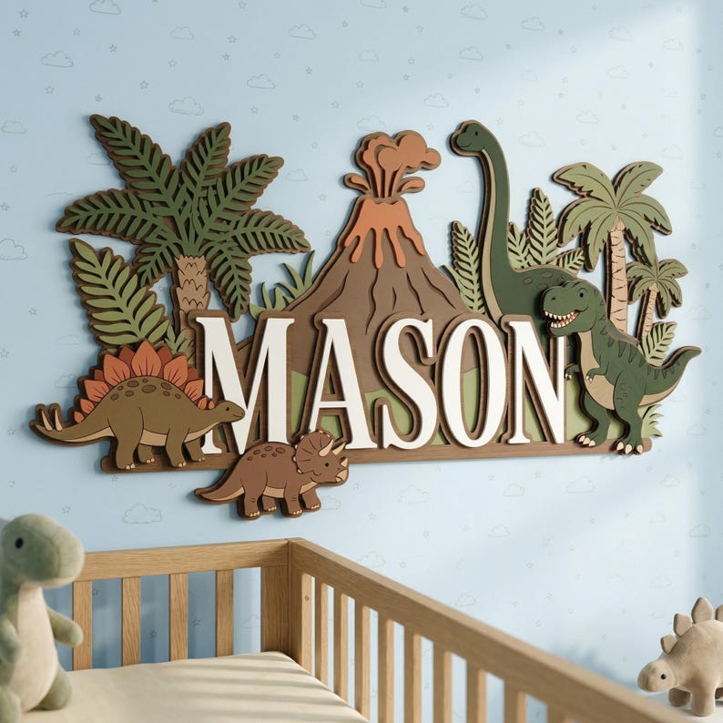 May include: A wooden wall decoration spelling "MASON" in white, with a dinosaur theme. It features a volcano, palm trees, and dinosaurs in green, brown, and orange. The background is light blue with cloud and star details, suitable for a child's room.