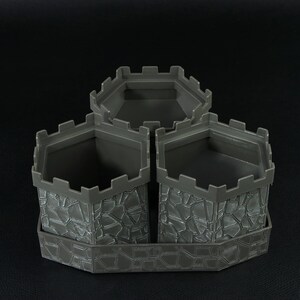 May include: A gray plastic castle-themed desk organizer with three sections. Each section has a stone-like texture and a crenelated top, resembling castle turrets. The organizer sits on a matching base.