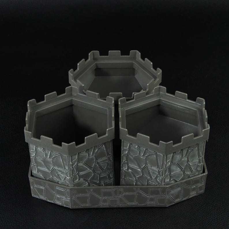 May include: A gray plastic castle-themed desk organizer with three sections. Each section has a stone-like texture and a crenelated top, resembling castle turrets. The organizer sits on a matching base.