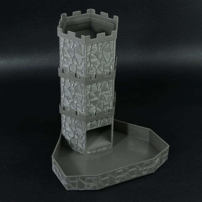 May include: Gray plastic dice tower in the shape of a castle tower. The tower has a textured stone pattern and a tray at the base. The top of the tower has a crenelated design.