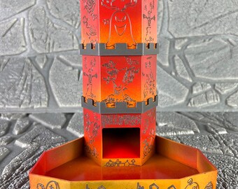 May include: A Halloween-themed dice tower in shades of red, orange, and yellow. The tower features a ghost and other spooky graphics. The base has a graveyard and pumpkin design. The text "HALLOWEEN" is visible on the tower.