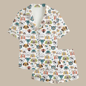 Peut inclure: Ensemble de pyjama blanc avec un motif répété de diverses races de chiens de plusieurs couleurs. La chemise boutonnée à manches courtes et le short assorti ont un col et sont faits d'une matière douce et confortable.