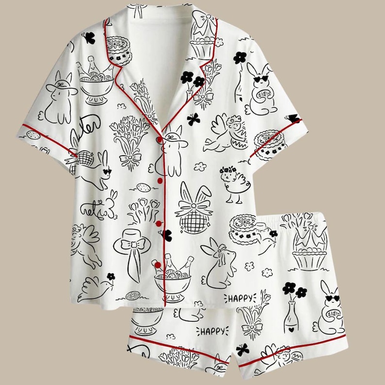 Peut inclure: Ensemble de pyjama blanc avec un motif noir et rouge. L'ensemble comprend une chemise boutonn&eacute;e &agrave; manches courtes et un short assorti. L'imprim&eacute; repr&eacute;sente des lapins, des fleurs, des g&acirc;teaux et le mot "HAPPY".