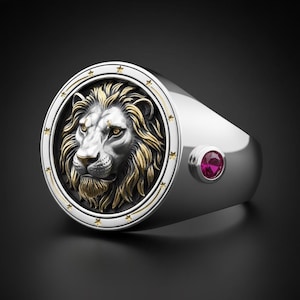 Può includere: Anello d'argento con una testa di leone dettagliata, criniera dorata e dettagli. L'anello presenta una faccia circolare con dettagli a stella e una piccola gemma rossa rotonda. Il design è ambientato su uno sfondo scuro.