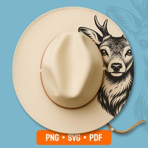 Könnte beinhalten: Ein cremefarbener Hut im Fedora-Stil mit einem braunen Lederband und Kinnriemen. Der Hut zeigt eine detaillierte Schwarz-Weiß-Illustration eines Hirschkopfes an der Seite. Das Bild enthält auch den Text "PNG • SVG • PDF" in einem orangefarbenen Rechteck.