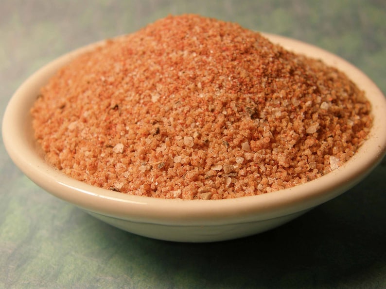 May include: A white bowl filled with a brown and orange spice blend.