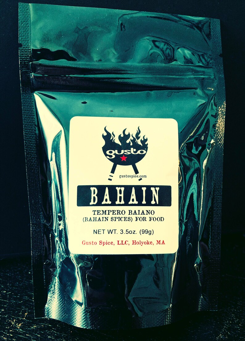 以下が含まれることがあります： 白いラベルが付いた黒い再封可能なポーチ。ラベルには「BAHAIN TEMPERO BAIANO (BAHAIN SPICES) FOR FOOD NET WT. 3.5oz. (99g) Gusto Spice, LLC, Holyoke, MA」と記載されています。ラベルには、炎が燃え盛るグリルと赤い「gusto」の文字が描かれた赤と黒のロゴも付いています。