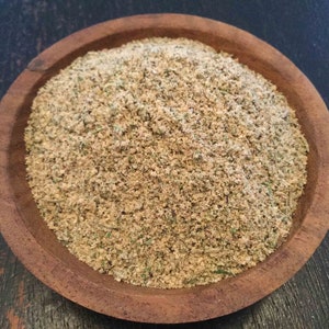 Puede incluir: Un cuenco de madera lleno de una mezcla de especias de color marr&oacute;n claro. La mezcla de especias parece ser una mezcla de hierbas y especias.