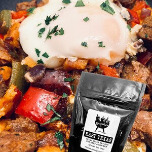 以下が含まれることがあります： サツマイモ、ピーマン、ソーセージを盛り合わせた朝食のプレートのクローズアップ。プレートの上に目玉焼きが乗っている。手前に、ビーフ＆チキン用のイーストテキサス・テキサススタイル・ドライラブが入った小さな黒い袋がある。袋には「gusto」と「etsy.com/shop/gustospice」の文字が書かれている。