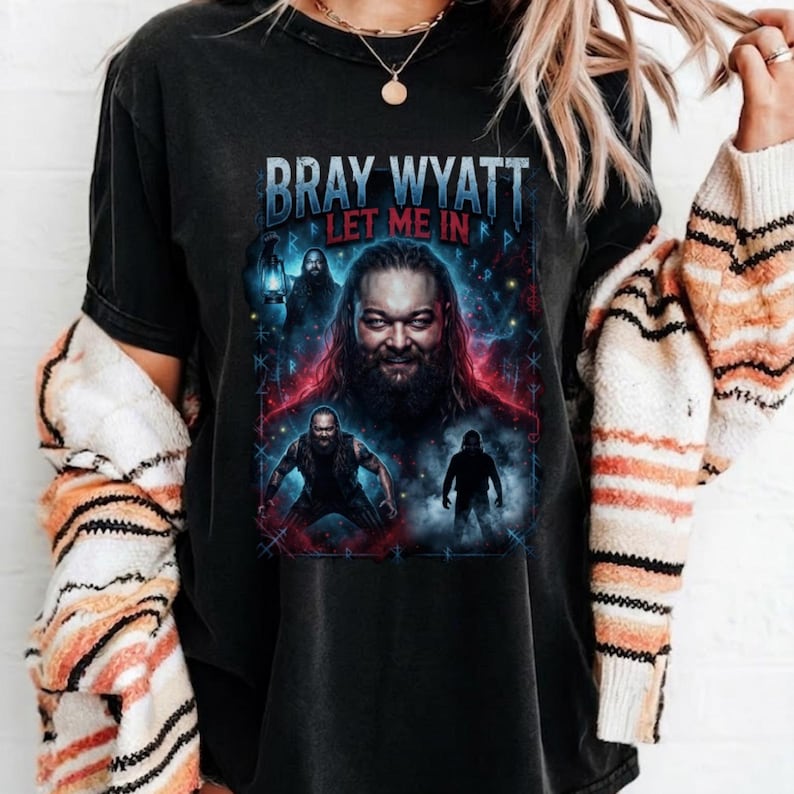 May include: A black short-sleeve t-shirt featuring a graphic print of Bray Wyatt. The design includes the text BRAY WYATT and LET ME IN, with multiple depictions of the figure surrounded by blue and red lighting effects and runic symbols.