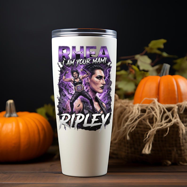 May include: A white stainless steel tumbler featuring a graphic print of a wrestler with purple lightning effects. The text reads RHEA I AM YOUR MAMI RIPLEY in bold lettering. The design includes a portrait and a full-body action pose of the athlete.